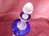 une bouteille en verre bleu avec un bouchon en cristal, posée sur un tissu rouge