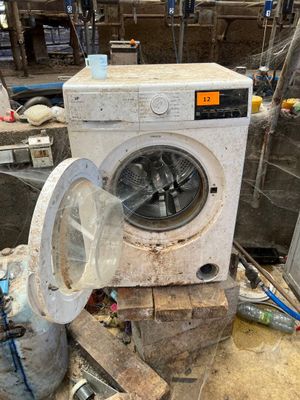 une machine à laver sale posée par terre dans une pièce