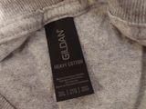 grey sweater with black label on it sitting on a bed