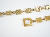 two pieces of gold bracelets on a white surface