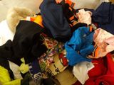 a pile of clothes on a bed next to a teddy bear