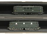 deux trains miniatures posés dans une boîte sur une surface blanche