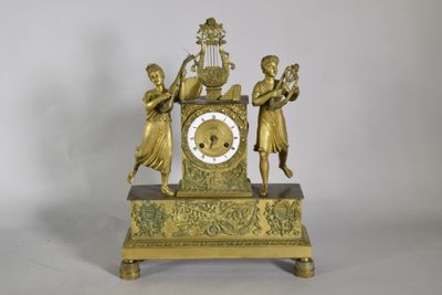 a gold clock with three girls on it and a bird in the middle