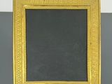 un cadre doré avec un tableau noir posé sur un support
