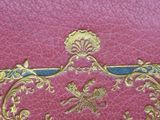 an old pink book with gold decoration on the cover