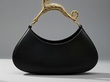un sac à main noir muni d'une poignée dorée, posé sur une table