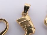 three gold pendants of different shapes and sizes on a white surface