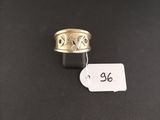 a gold ring with a black band and a white tag on a black surface