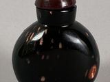 a small black vase with a red lid sitting on a table