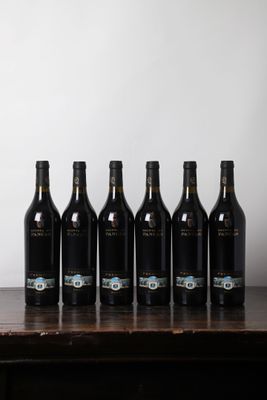 six bouteilles de vin sont alignées sur une table en bois