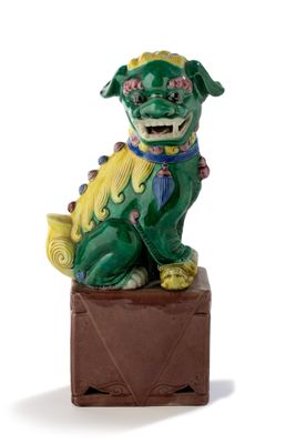 statue d'un chien vert et jaune assis sur un bloc de bois