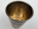 a metal cup that is sitting on a white surface
