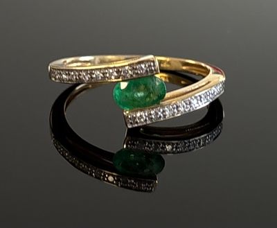 an emerald and diamond ring on a black surface
