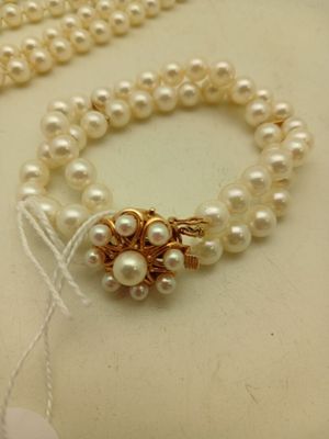 un collier de perles avec un fermoir en or et un collier de perles blanches avec un fermoir en or et un collier de perles blanches avec un fermoir en or et un collier de perles blanches avec un fermoir en or et un