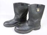 une paire de bottes de travail noires posées sur une surface blanche, sur fond blanc