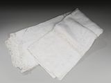 trois pièces de linge blanc ornées de dentelle, posées sur une table