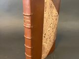 an old book with a brown cover sitting on top of a table
