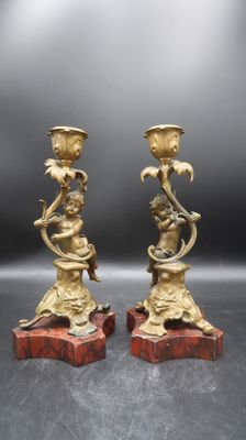 paire de bougeoirs anciens en laiton reposant sur des socles en marbre rouge
