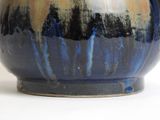 a close up of a blue and yellow vase on a white surface