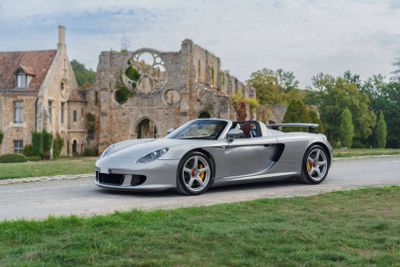 a silver sports car driving down the road in front of a castle