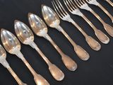 a lot of silver spoons and forks on a black table