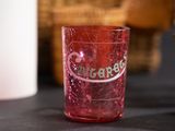 a red glass with a logo on it sitting on a table