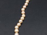 a close up of a pearl necklace on a black surface