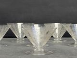 six clear wine glasses sitting on top of a table next to a wall