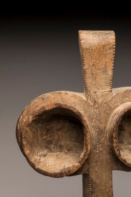 un gros plan d'une croix en bois sur laquelle sont dessinés deux yeux