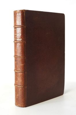an old book with a brown cover sitting on a white surface