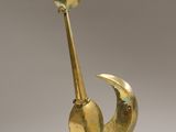 une sculpture en or représentant un oiseau avec un œil rouge sur la tête