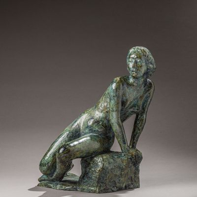 l'image d'une statue de bronze représentant une femme assise sur un rocher