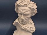 une sculpture blanche représentant la tête d'un homme sur fond bleu