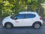 a picture of a white car parked in front of a fence