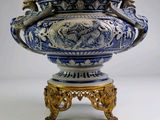 un grand vase bleu et blanc posé sur un socle doré