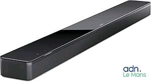 La barre de son est noire et est équipée d'une télécommande placée sur le dessus.