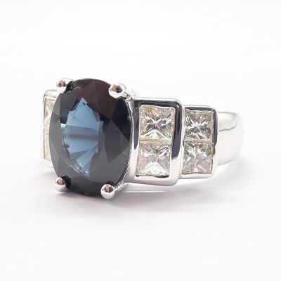 an image of a ring with a large blue stone surrounded by three smaller diamonds