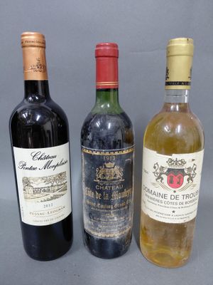 trois bouteilles de vin sont alignées sur une surface grise