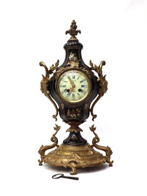 a black and gold clock on a stand on a white background