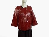 mannequin portant une veste et une jupe en cuir rouge, ainsi qu'un chapeau noir