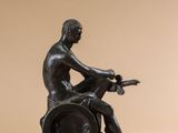 statue en bronze représentant un homme assis sur un tonneau, une guitare à la main