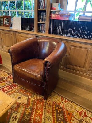 un fauteuil en cuir marron placé devant une bibliothèque