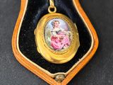 a gold locke with a picture of a woman in a pink dress on it