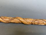 an old carved wooden stick with a snake on it