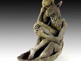 sculpture représentant une femme assise sur un rocher, tenant un chat dans ses bras