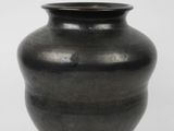 a black vase that is sitting on a white surface