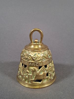 an old brass bell on a gray surface with a bird on it
