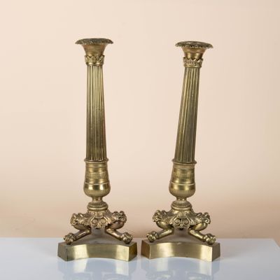 pair of antique brass candlesticks on a glass table