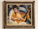 un tableau représentant une femme jouant de la guitare, accroché au mur