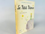 un livre sur lequel figure l'image d'un petit prince assis au sommet d'une colline